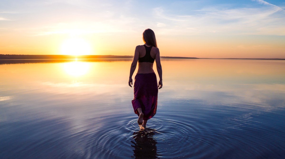 Frau steht mit langem Kleid im Wasser