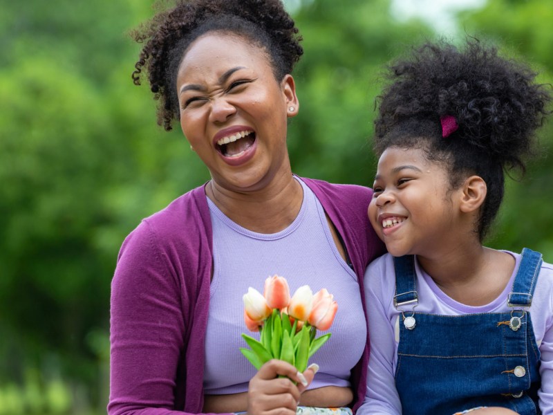 Mutter und Tochter lachend, Mutter hält Blumenstrauß