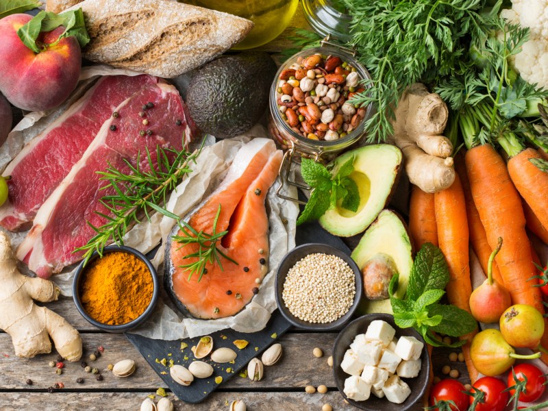 Die Ernährung bei Osteopathie; Obst, Gemüse, Fisch und Fleisch auf einem Holztisch