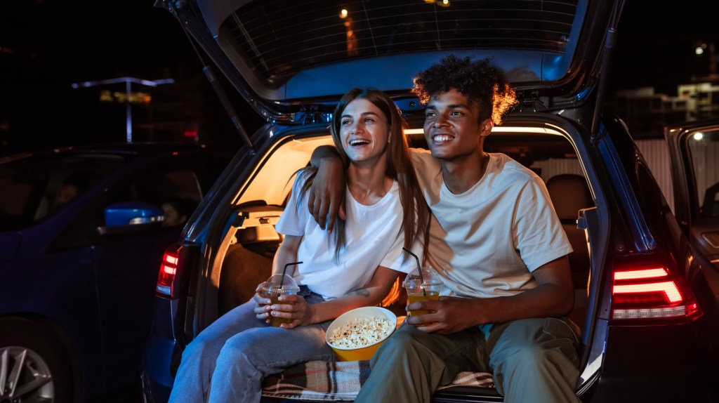 Pärchen auf Van, das einen Film guckt und Popcorn snackt