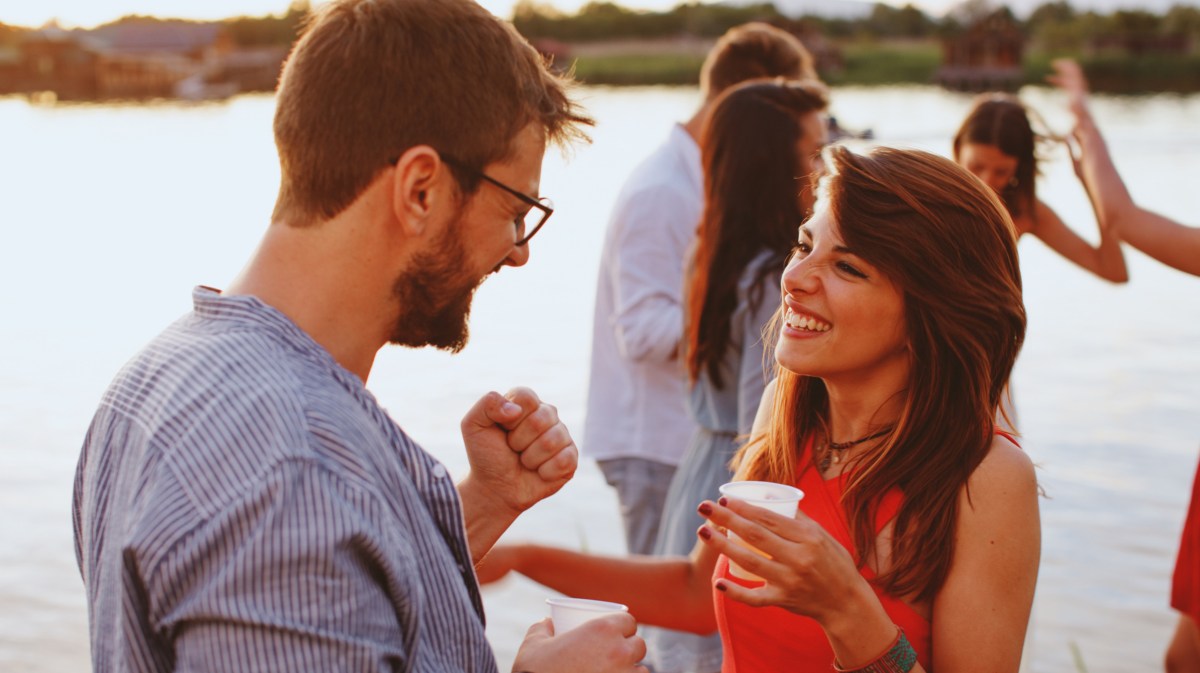 Mann und Frau, die an einem See stehen und sich lachend unterhalten