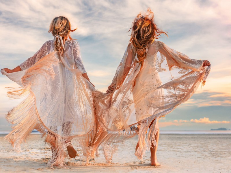 Zwei Frauen mit fließenden Kleidern am Strand