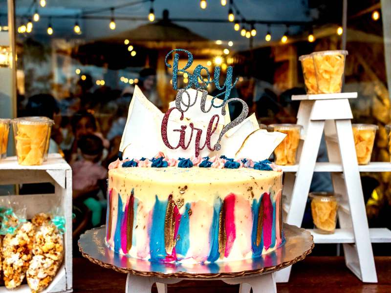 Kuchen im Schaufenster für eine Gender Reveal Party, mit einem Schild 'Boy or Girl' obendrauf.
