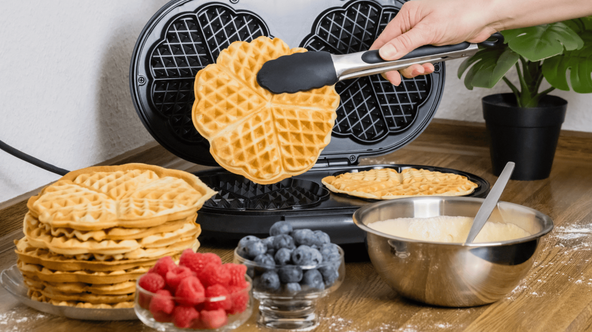 Person backt Herzwaffeln in Waffeleisen.