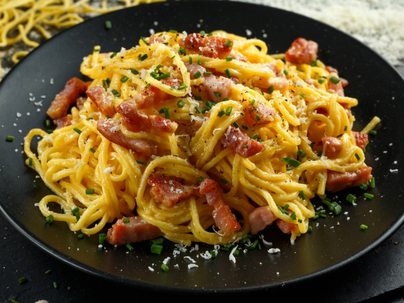 Spaghetti Carbonara auf einem dunklen Teller.