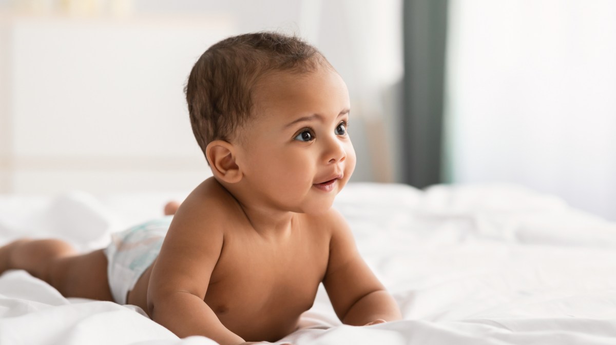 Baby auf Bett, dass sich mit den Händen abstützt