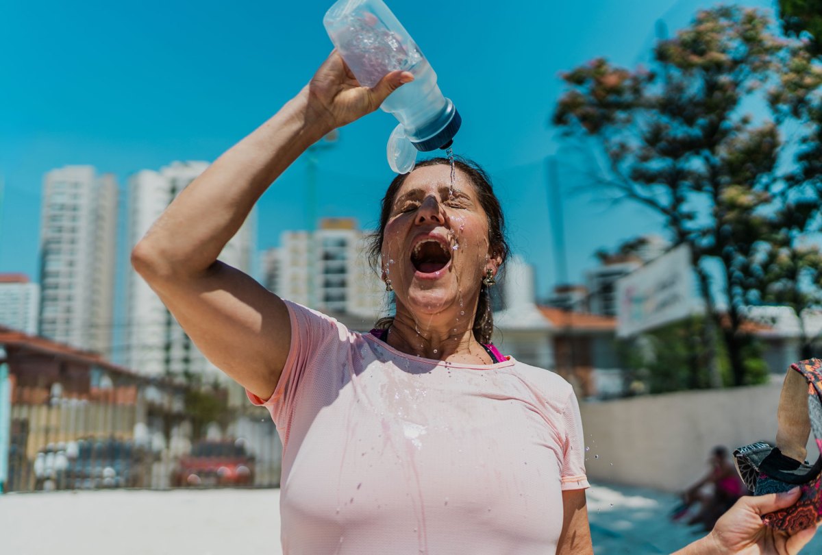 Frau, die sich mit einer Flasche Wasser abkühlt.