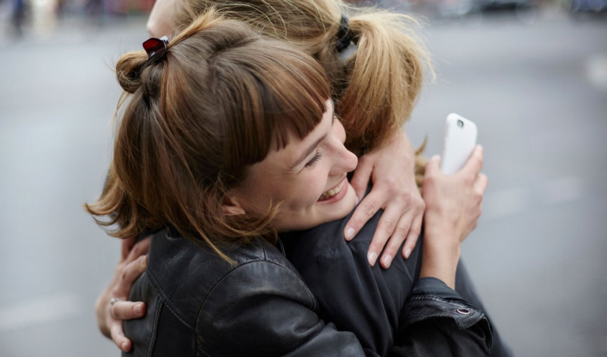 Zwei junge Frauen umarmen sich lachend