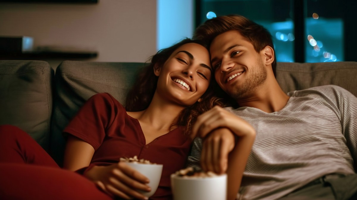 Frau und Mann auf Couch am Lachen mit Popcorn in der Hand