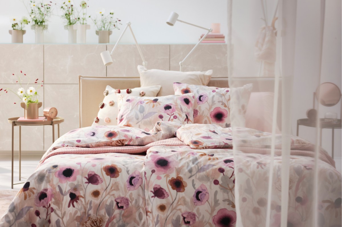 Hell eingerichtetes Schlafzimmer mit bunter Blumen-Bettwäsche