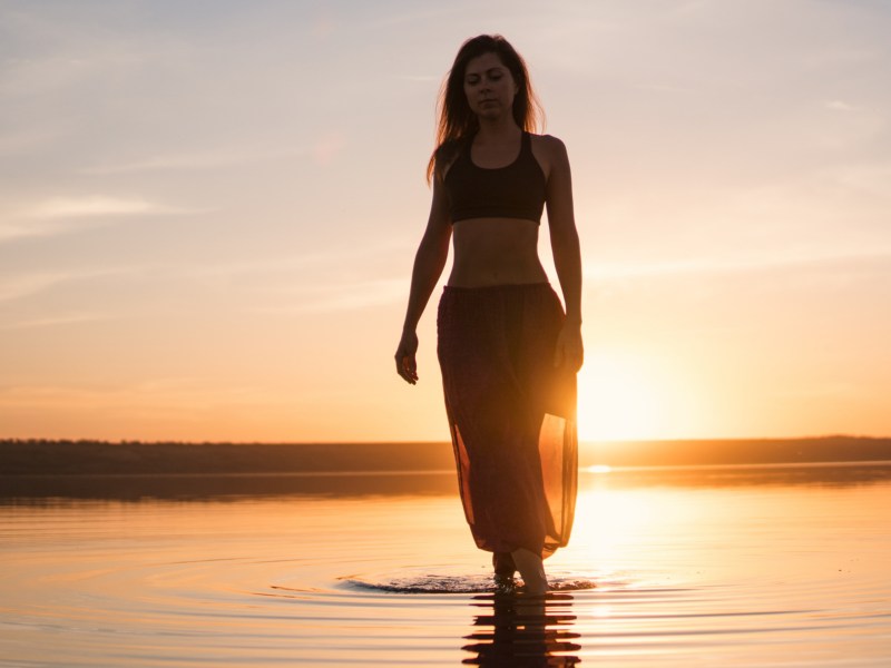 Frau am Strand, bei Sonnenuntergang