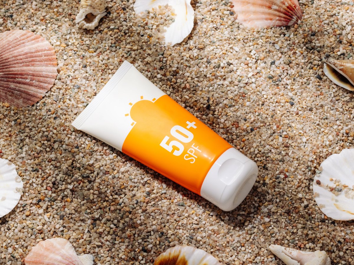 Eine Tube Sonnencreme, die im Sand liegt