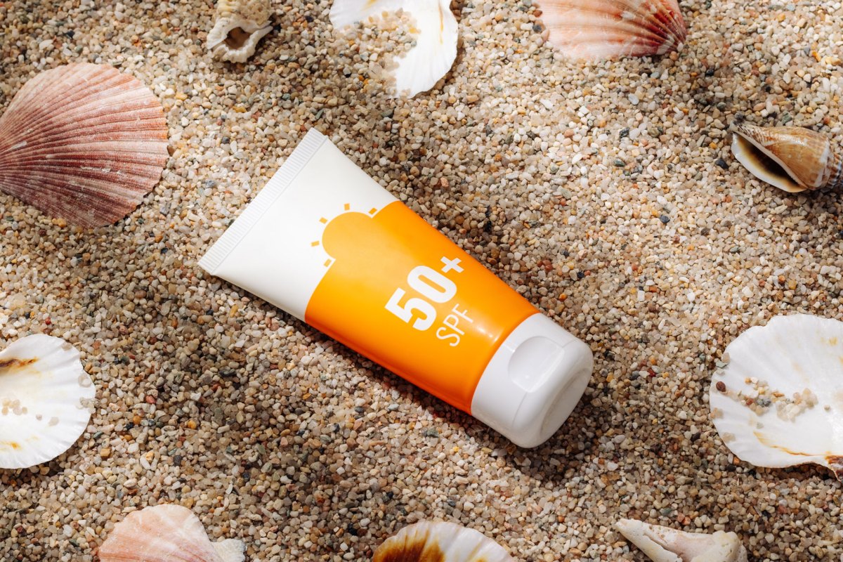 Eine Tube Sonnencreme, die im Sand liegt