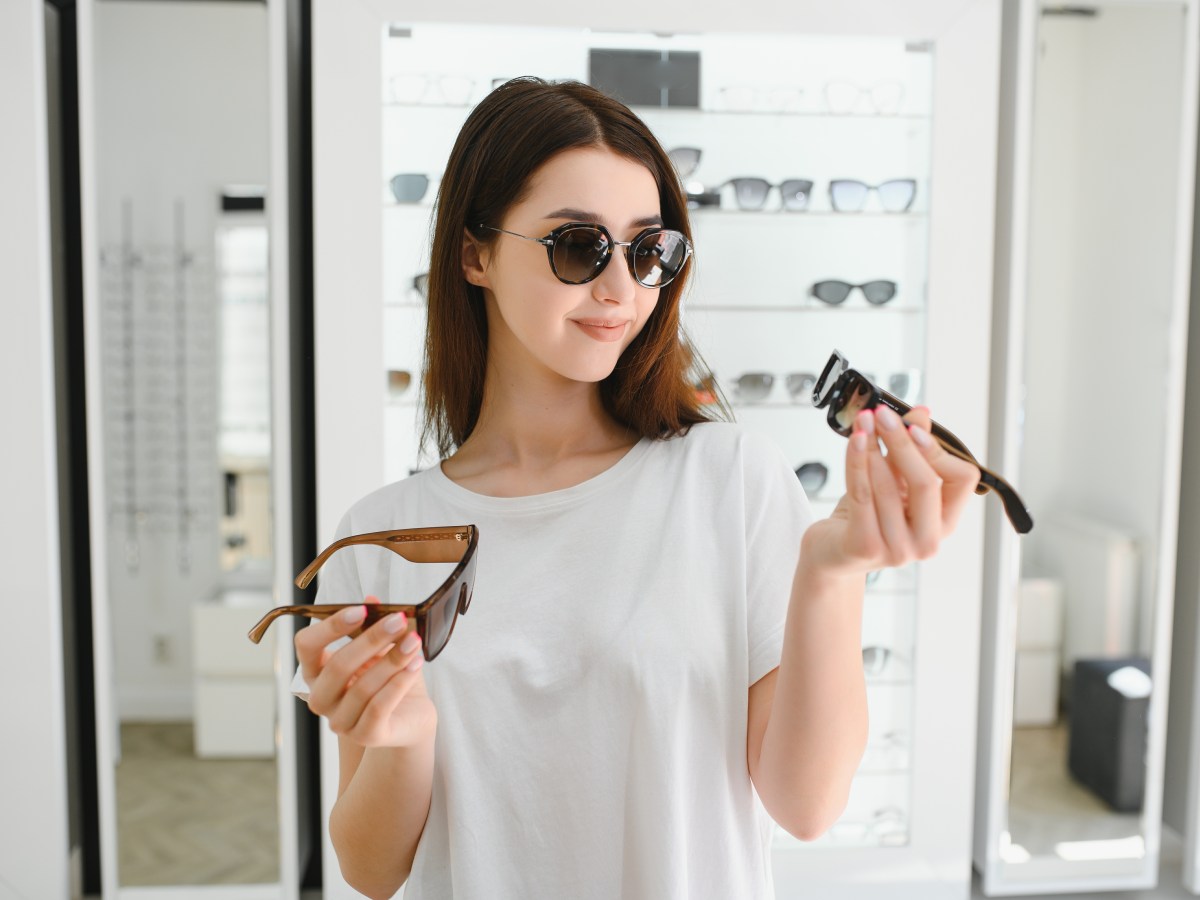 Frau, die beim Optiker mehrere Sonnenbrillen anprobiert