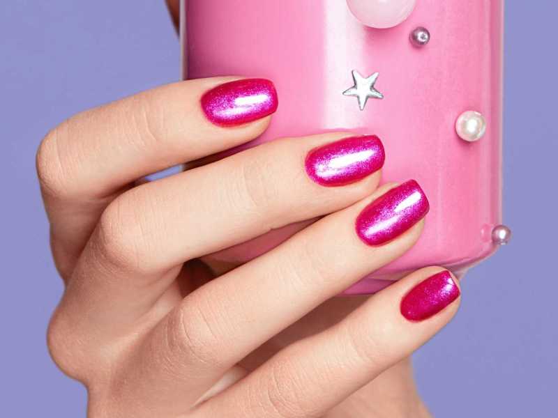 Pinke Nägel halten eine rosa Getränkedose fest