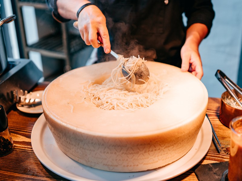 Großer Parmesan-Laib mit Nudeln in der Mitte.