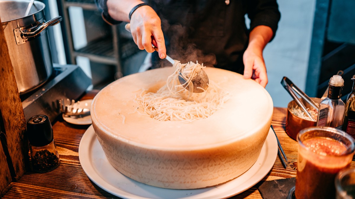 Großer Parmesan-Laib mit Nudeln in der Mitte.