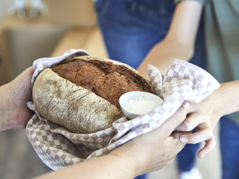 Person überreicht Paar Brot und Salz zum Einzug.