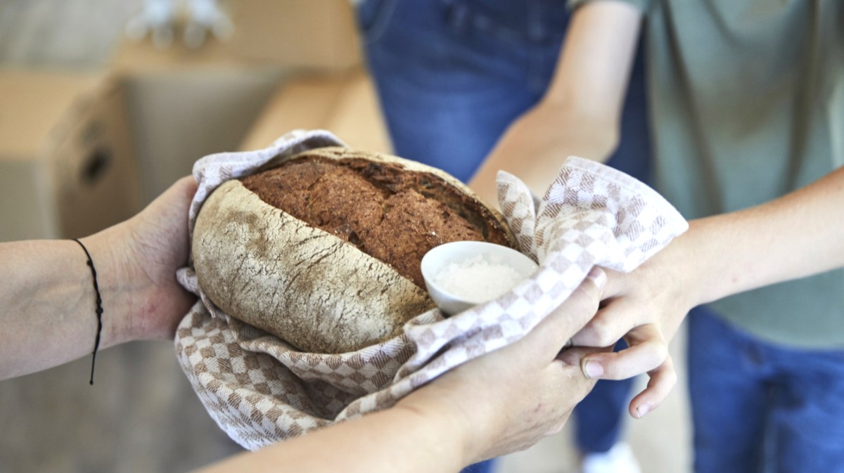 Person überreicht Paar Brot und Salz zum Einzug.