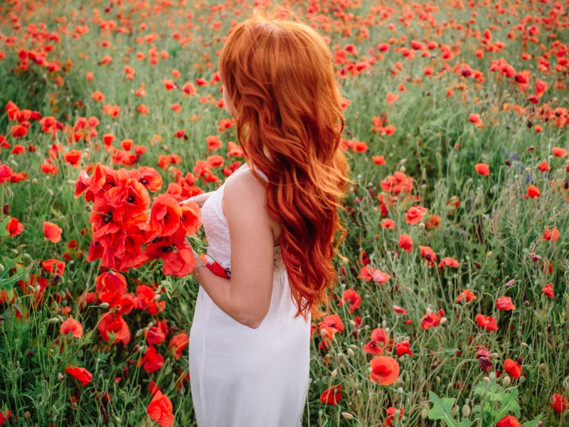 Frau mit roten Haaren steht in Feld.