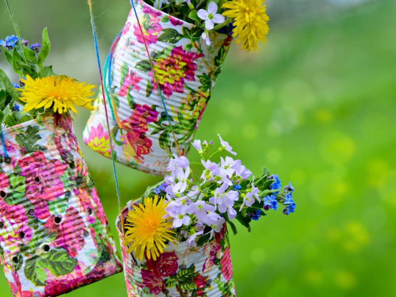 Hängende Blumenvasen aus alten Konservendosen mit Frühlingsblumen und buntem Muster