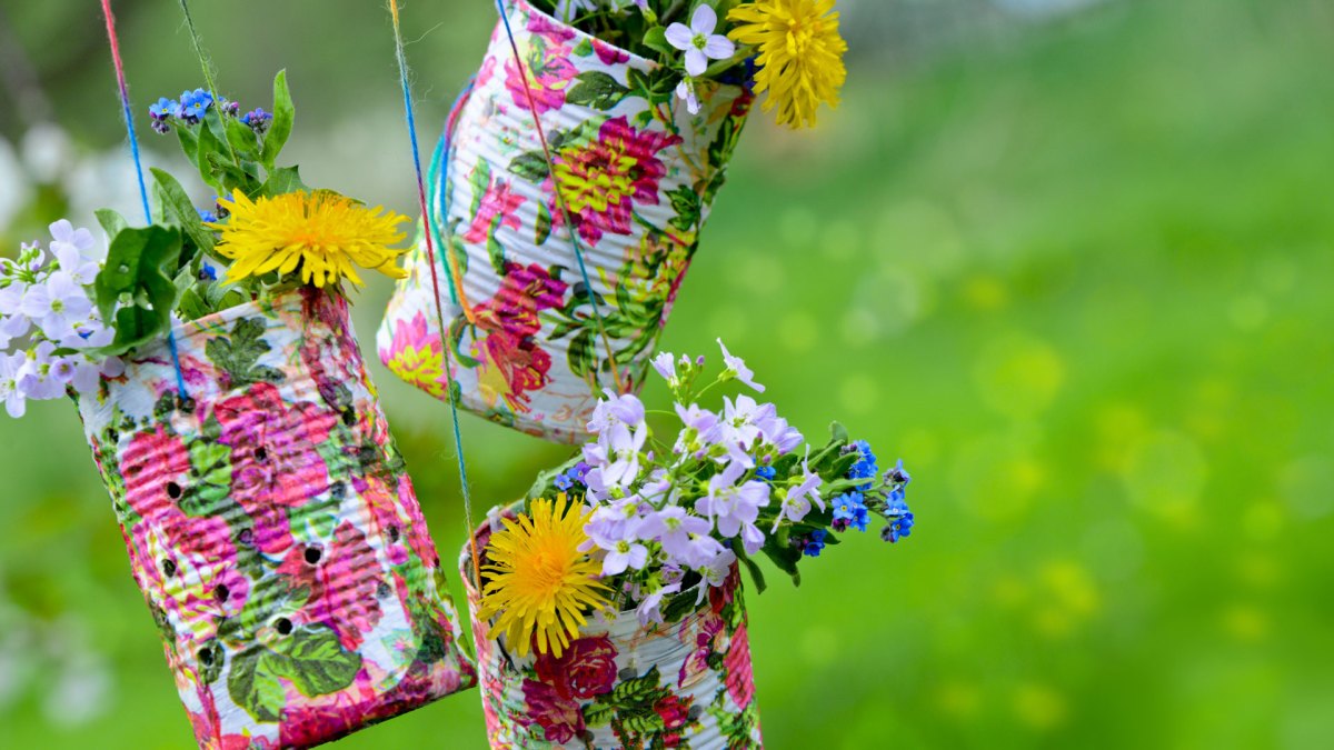 Hängende Blumenvasen aus alten Konservendosen mit Frühlingsblumen und buntem Muster