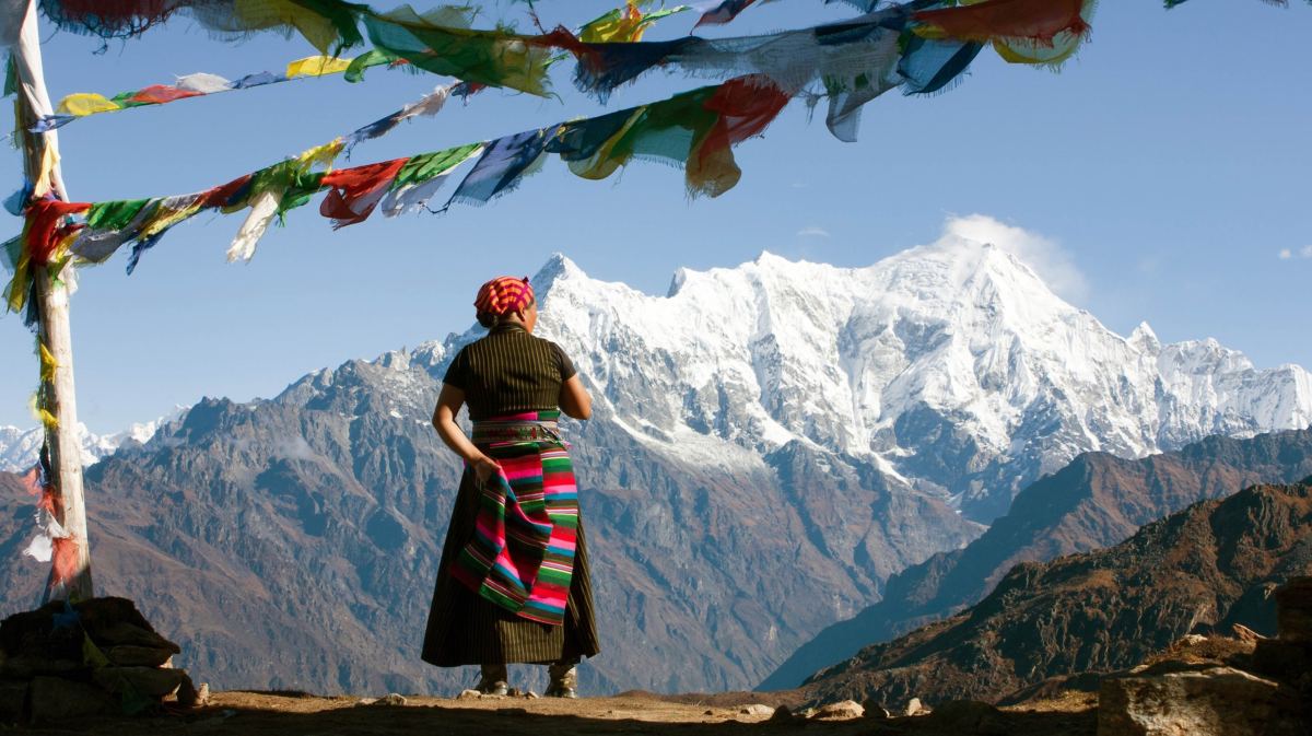 Ältere Frau aus Tibet schaut auf Berge.