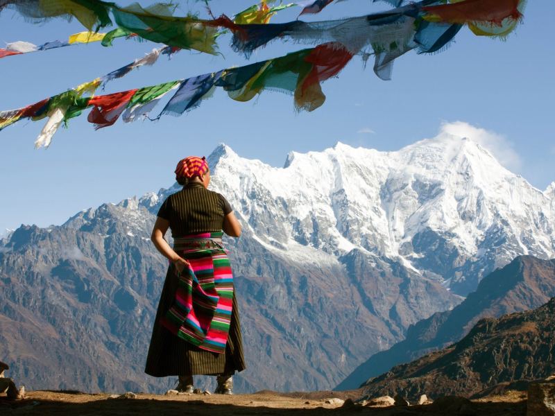 Ältere Frau aus Tibet schaut auf Berge.