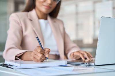 Frau im Job schreibt etwas auf.