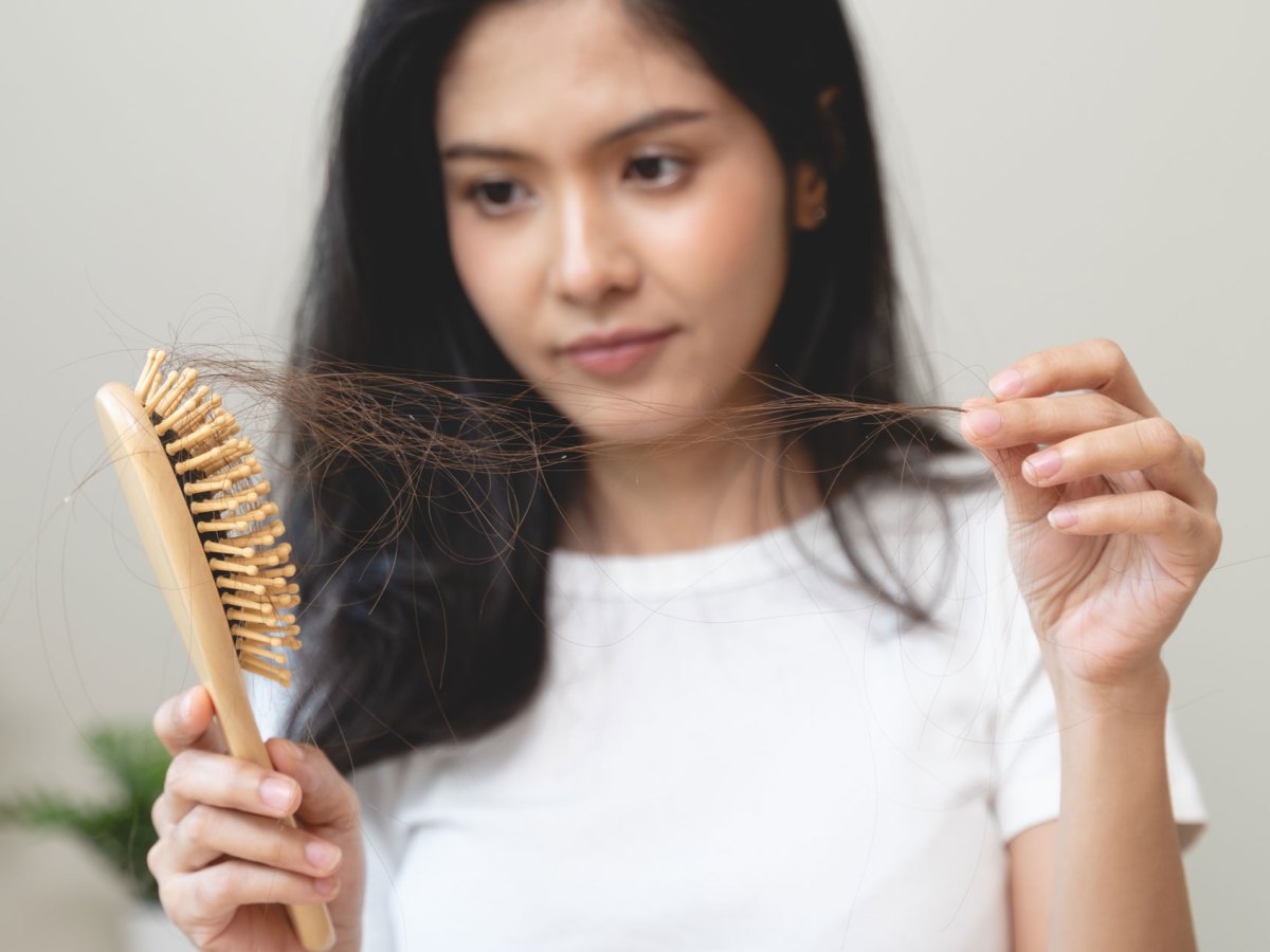 Frau, die Haarbüschel aus der Bürste zieht.