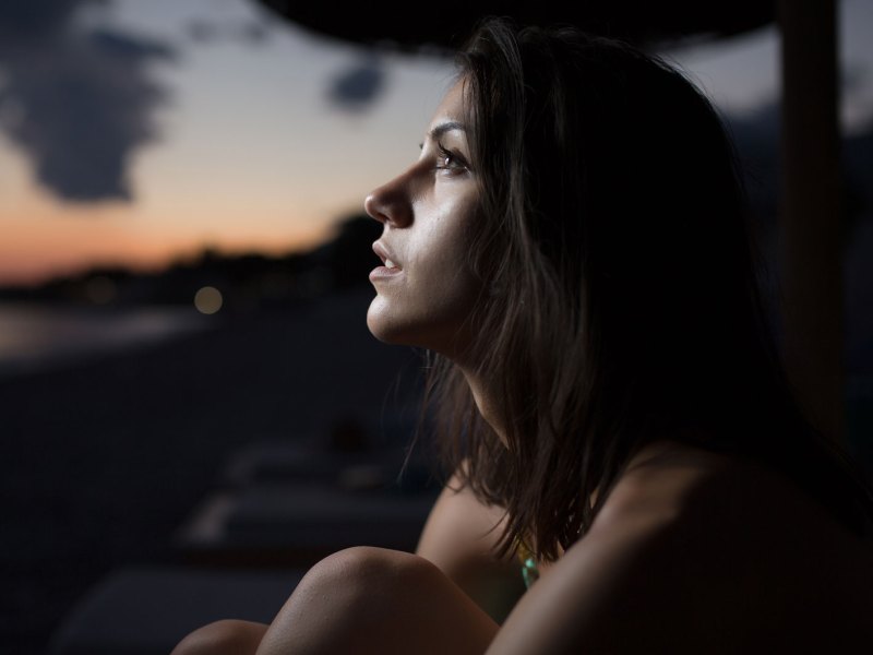 Frau schaut nachdenklich in den Abendhimmel.