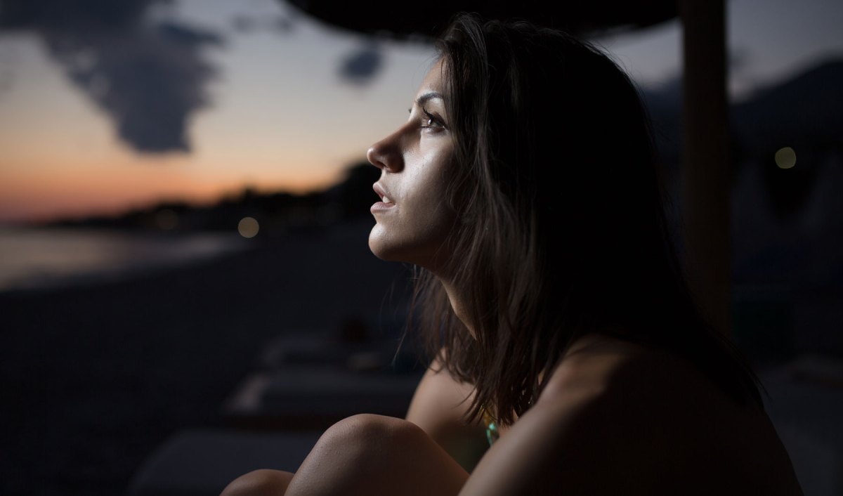 Frau schaut nachdenklich in den Abendhimmel.