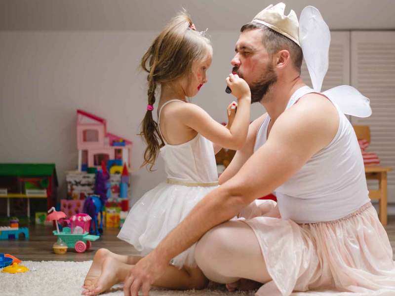 Kleines Mädchen schminkt ihren Papa als Prinzessin und hat Spaß.