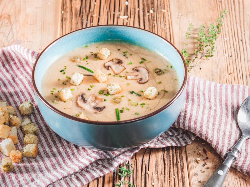 Champignoncremesuppe in einer blauen Schale. Dazu Croûtons.