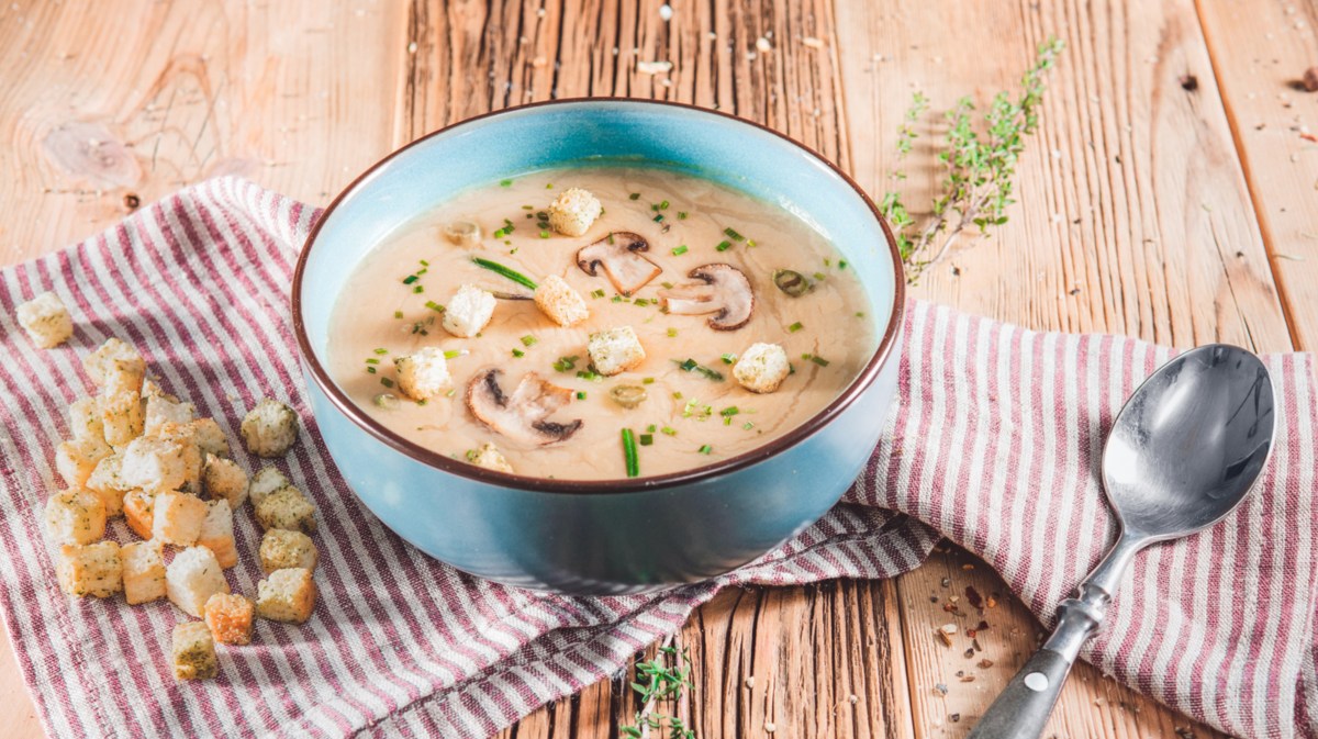 Champignoncremesuppe in einer blauen Schale. Dazu Croûtons.