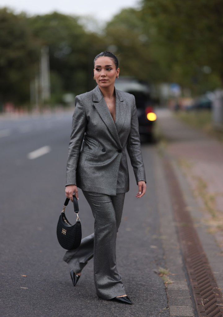 Frau im eleganten Hosenanzug mit schwarzer Tasche.