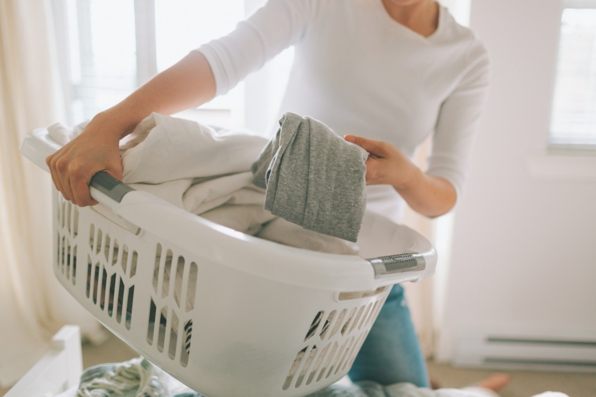 Frau hält Wäschekorb und macht den Haushalt