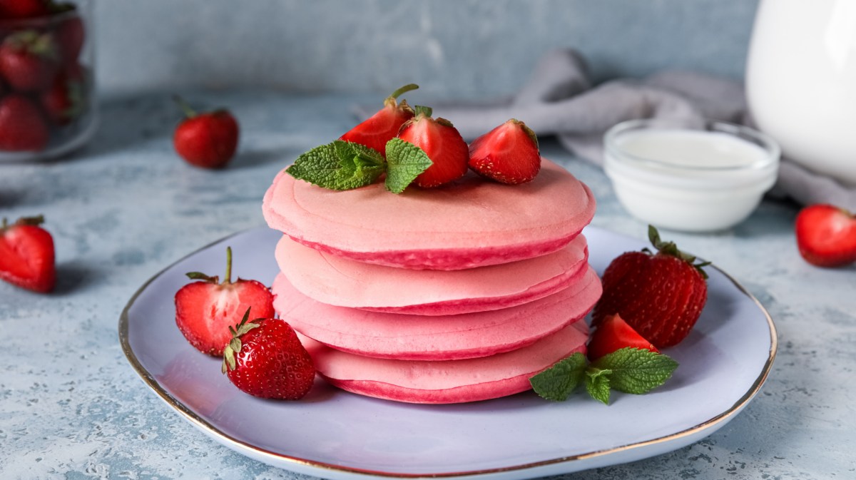 Pinke Pancakes mit Erdbeeren serviert auf einem Teller