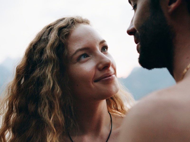 Eine junge Frau schaut einem Mann lächelnd in die Augen.