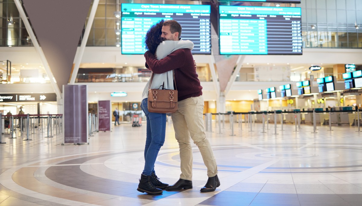 Paar in einer Fernbeziehung, dass sich am Flughafen umarmt