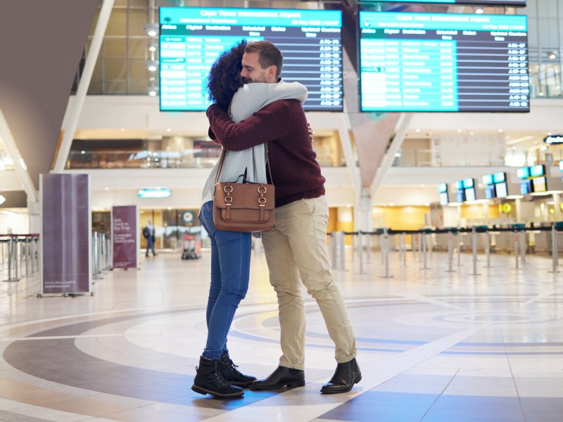Paar in einer Fernbeziehung, dass sich am Flughafen umarmt