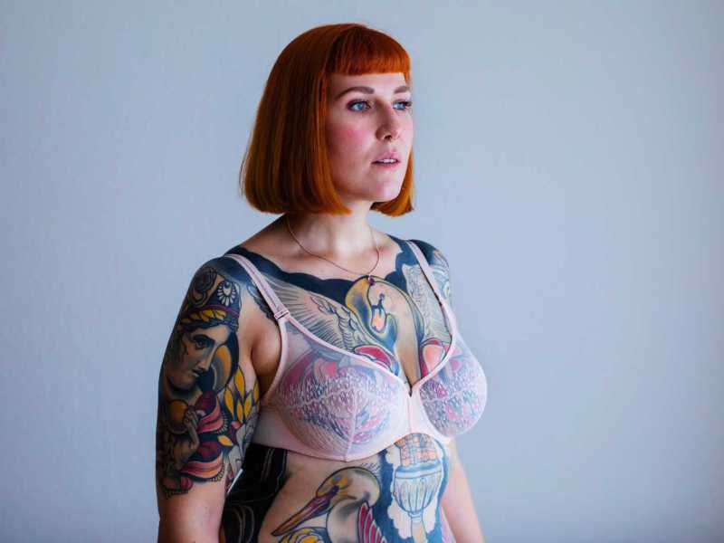 Rothaarige Frau mit Ganzkörpertattoos.