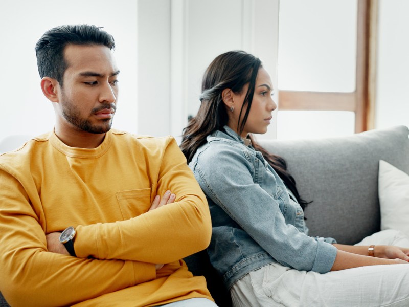 Wütendes Pärchen sitzt auf Sofa.