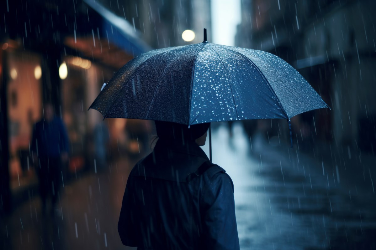 Person mit Regenschirm in dunkler Straße