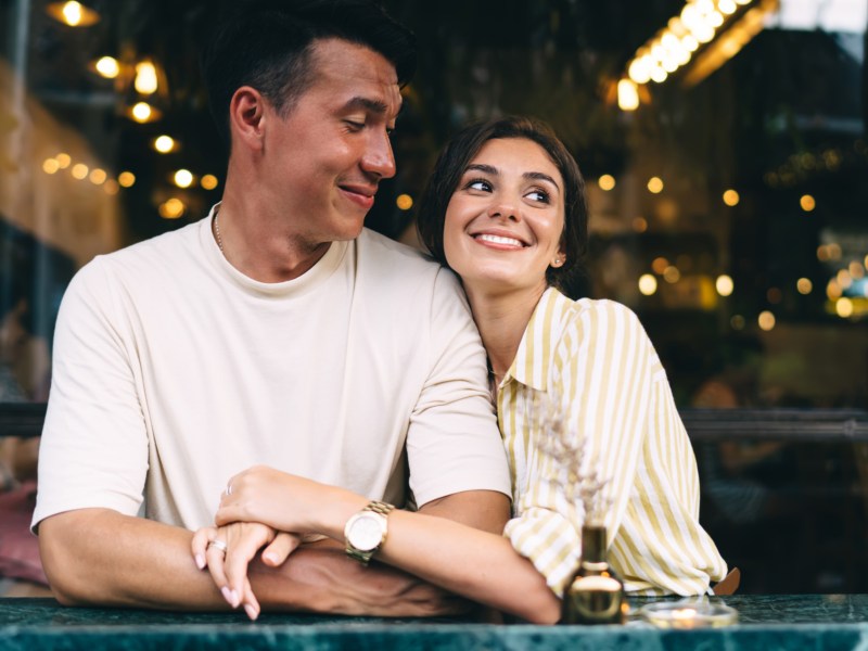 Frau und Mann in einem Café, die sich gegenseitig umarmen und anlächeln