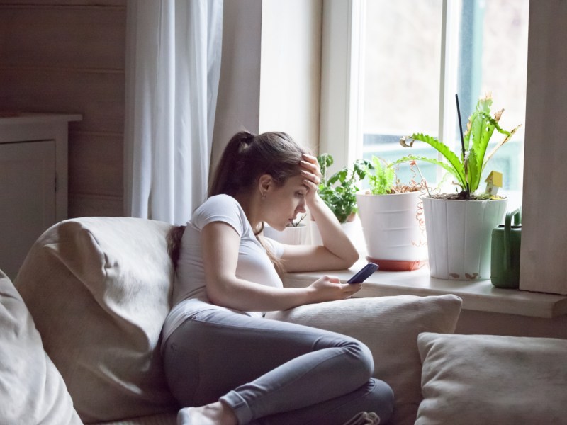 Frau auf einem Sofa mit Handy in der Hand