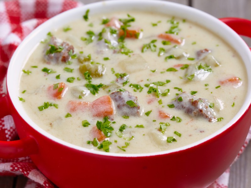 Cremige Hackfleisch-Kohlrabi Suppe in einer roten Suppenschüssel.