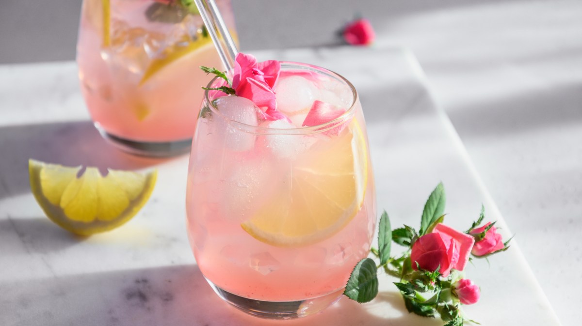 Rosa farbener Cocktail mit Limettenscheiben.