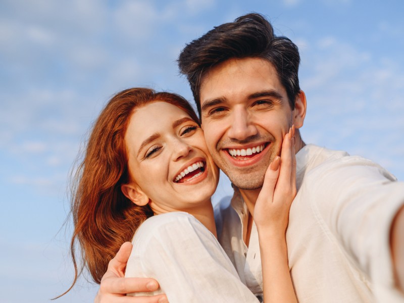 Mann und Frau, die beide in die Kamera lachen und ein Selfie machen