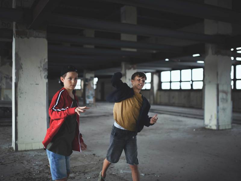 Zwei Teenie-Jungs werfen in einem verlassenen Industriegebäude mit Steinen.